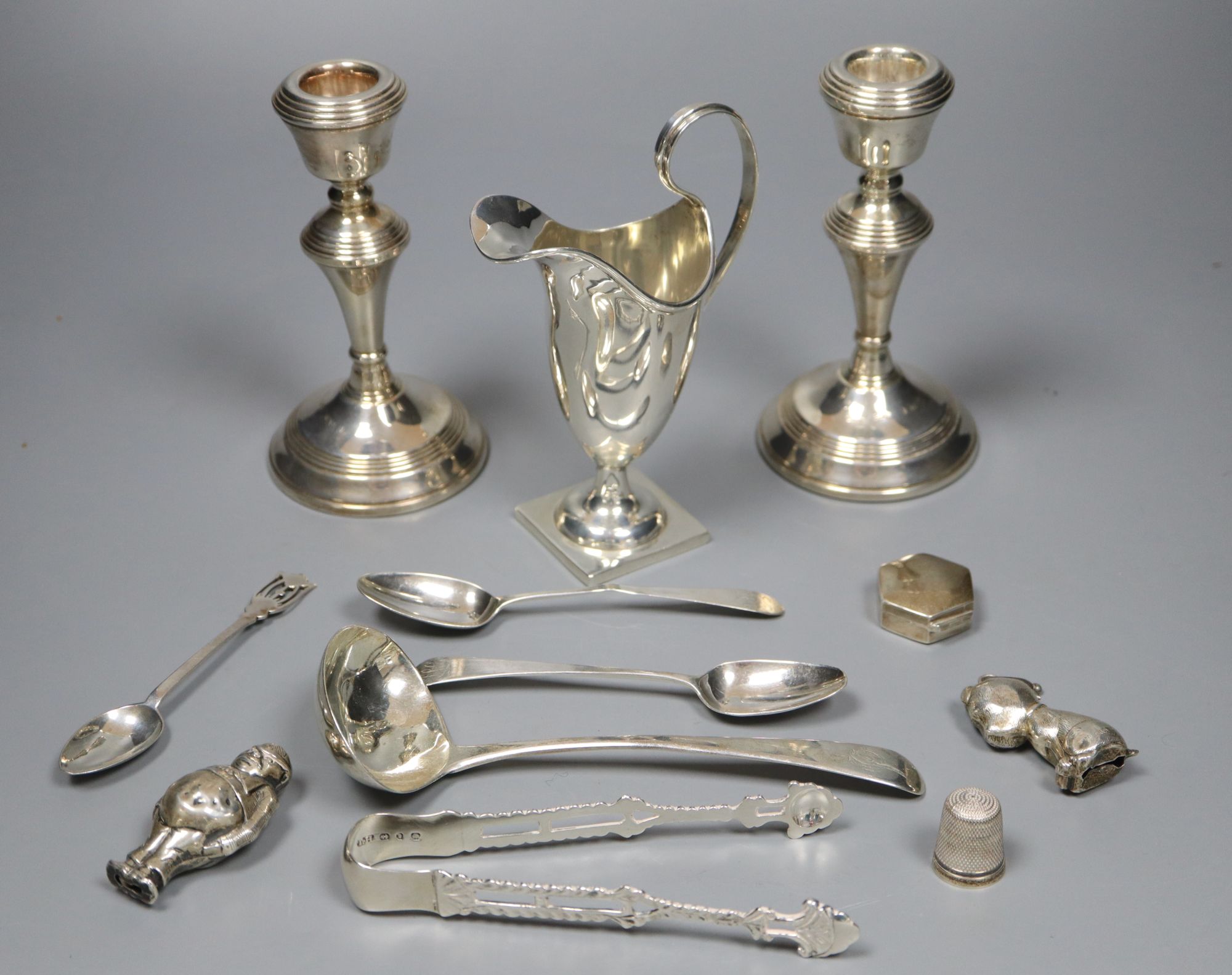 A quantity of small silver to include a pair of candlesticks, sauce ladle, cream jug etc and a silver plated rattle,